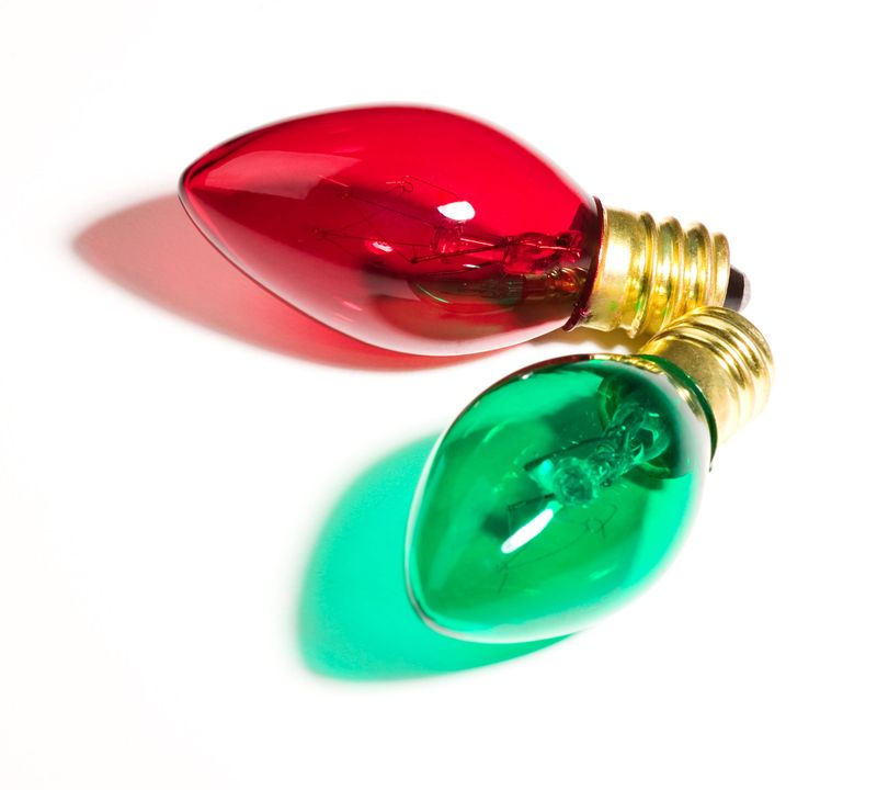 one green and one red colored christmas light on white background.