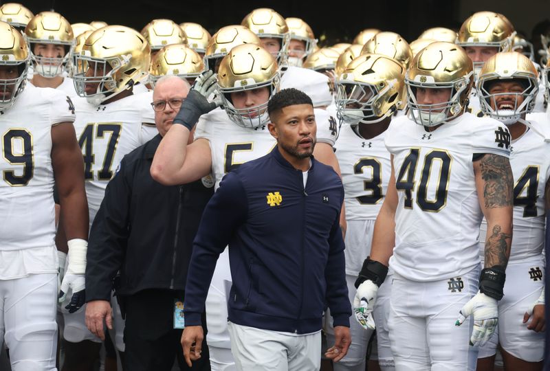 Nov 15, 2025; Pittsburgh, Pennsylvania, USA; Notre Dame Fighting Irish head coach Marcus Freeman (middle) leads the team onto the field to play the Pittsburgh Panthers at Acrisure Stadium. Mandatory Credit: Charles LeClaire-Imagn Images