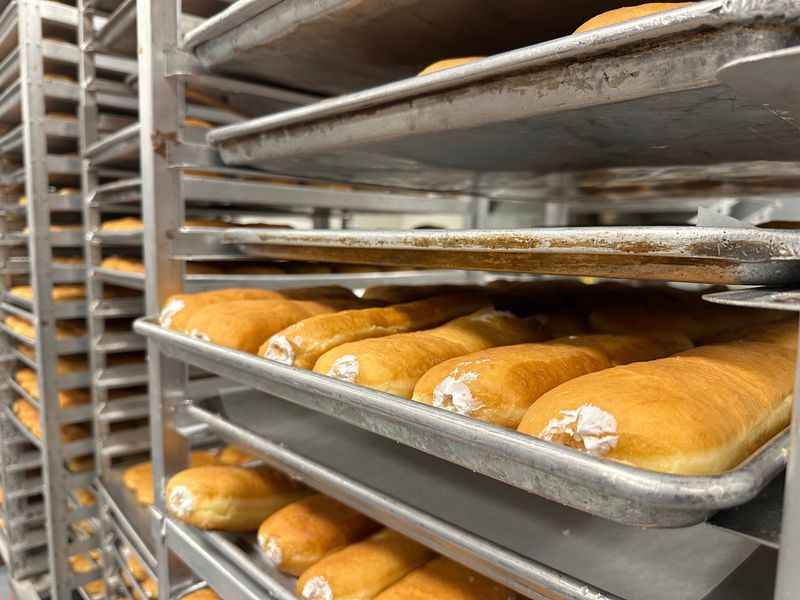 Trays of fresh long john doughnuts wait to be iced in the back kitchen of Mary Lou's Donuts.
