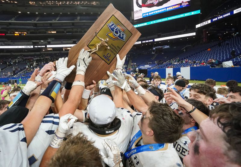 Bishop Dwenger Saints celebrate with the trophy Saturday, Nov. 29, 2025, during the IHSAA Class 4A state championship game at Lucas Oil Stadium in Indianapolis.