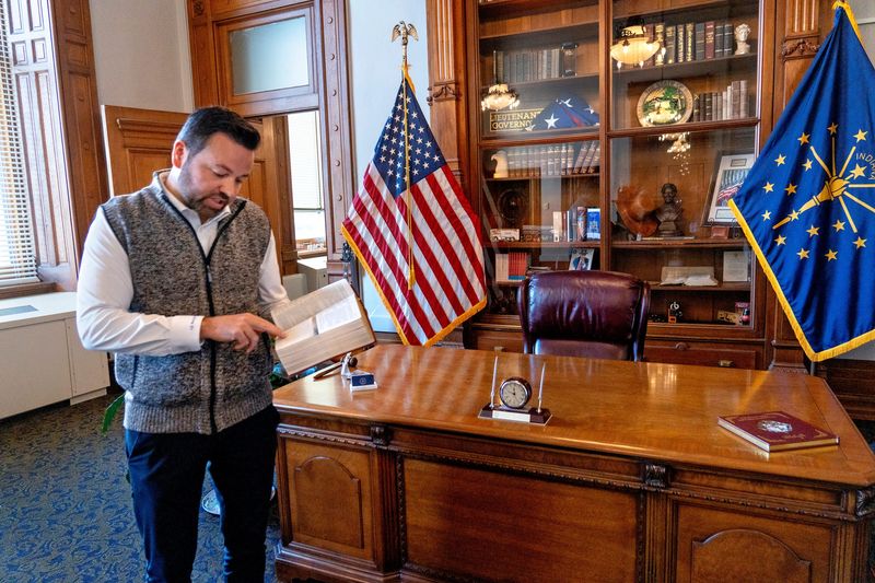Lt. Gov. Micah Beckwith looks in one of the several Bibles he has in his office Monday, Oct. 20, 2025 at the Indiana Statehouse.