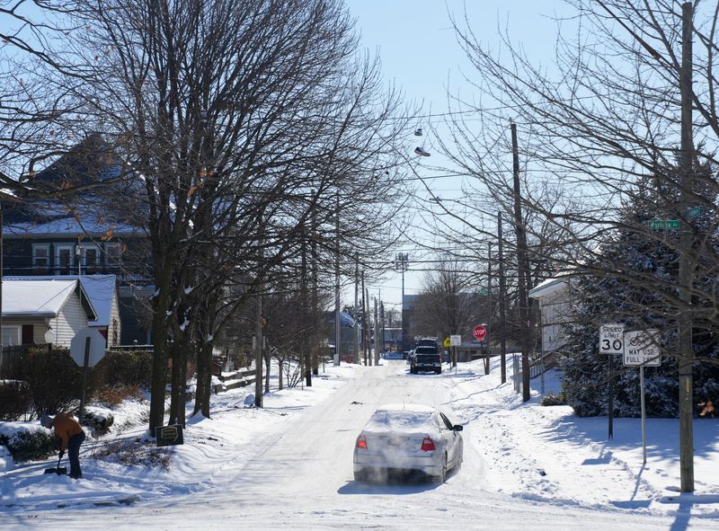 A car travels along a snowy road Sunday, Dec. 14, 2025, along North Highland Avenue in Indianapolis.