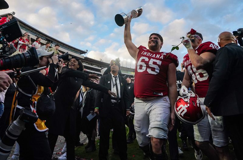 Indiana Hoosiers offensive lineman Carter Smith (65) holds up the trophy while walking off the field Thursday, Jan. 1, 2026, after defeating Alabama Crimson Tide in the 112th annual Rose Bowl game in Pasadena.