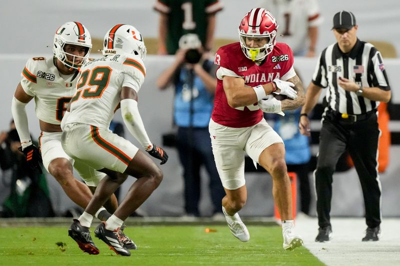 Indiana Hoosiers wide receiver Elijah Sarratt (13) rushes along the sideline as Miami (FL) Hurricanes defensive back Jr. Romanas Frederique (29) looks to stop him Monday, Jan. 19, 2026, during the College Football Playoff National Championship college football game at Hard Rock Stadium in Miami Gardens.
