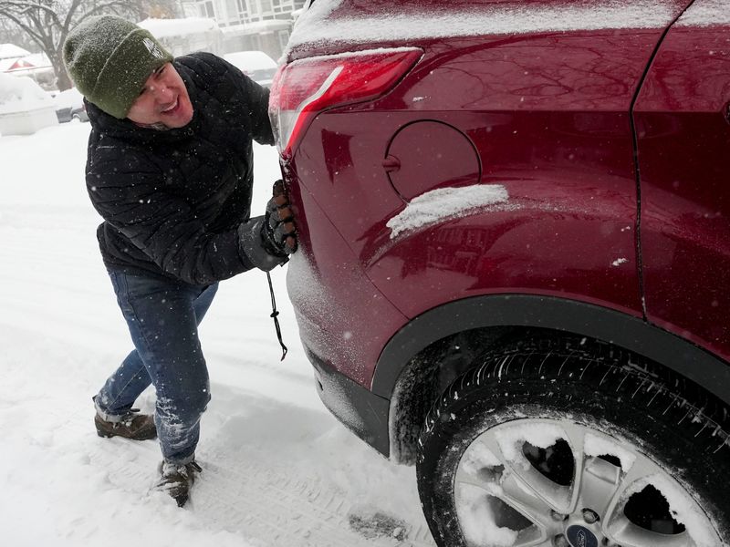Jason Gray pushes a stuck car as snow falls Sunday, Jan. 25, 2026, in the Woodruff Place neighborhood in Indianapolis.