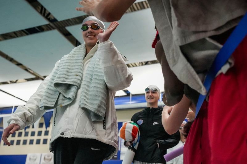 Fishers’ Audrey Wolf high-fives Tigers students while walking to the starting block Saturday, Feb. 7, 2026, during a sectional swim and dive meet at Hamilton Southeastern High School in Fishers. The Fishers Tigers won with 539 points and the Hamilton Southeastern Royals placed second with 504 points.