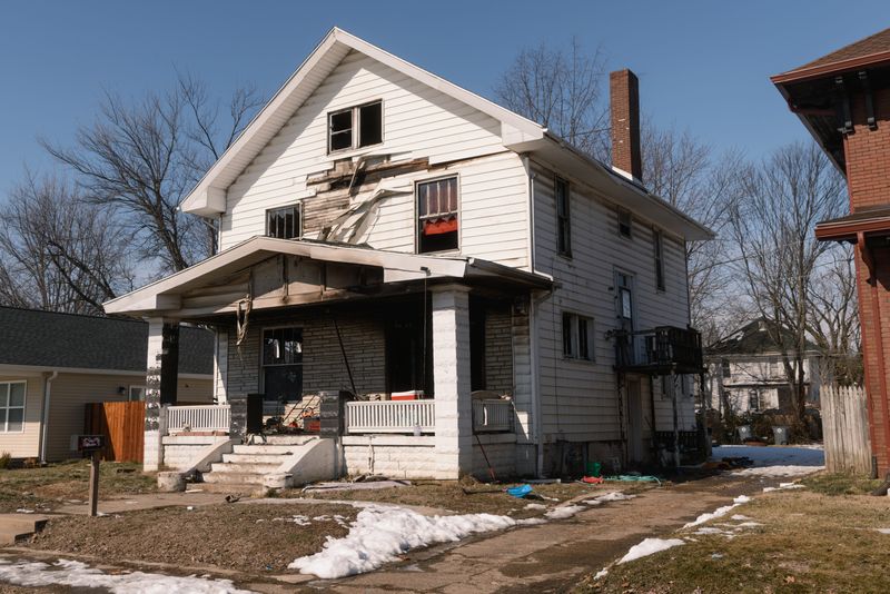The two-story home at 604 E. Powell Street bears shattered windows, soot and debris on Monday, Feb .9, 2026, one day after a fire killed two children and critically wounded a third.