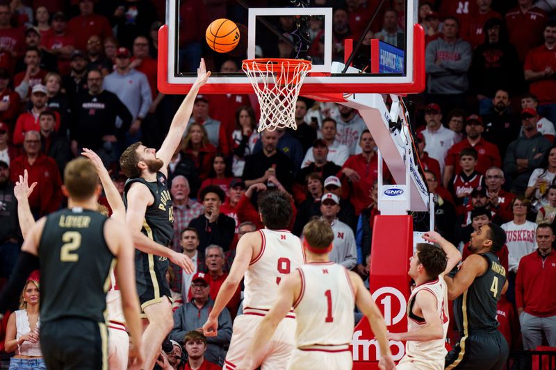 Feb 10, 2026; Lincoln, Nebraska, USA; Purdue Boilermakers center Oscar Cluff (45) shoots the ball against Nebraska Cornhuskers forward Berke Buyuktuncel (9) and forward Pryce Sandfort (21) during the first half at Pinnacle Bank Arena. Mandatory Credit: Dylan Widger-Imagn Images
