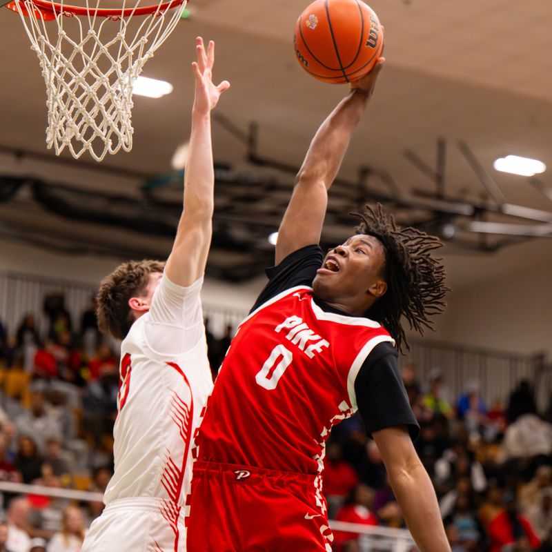 Pike High School junior Jahari Miller (0) prepares to dunk while being defended by Lawrence North High School senior Duke Karnes (13) during the first half of a Metropolitan Interscholastic Conference championship basketball game, Friday, Feb. 20, 2026, at Lawrence North High School.