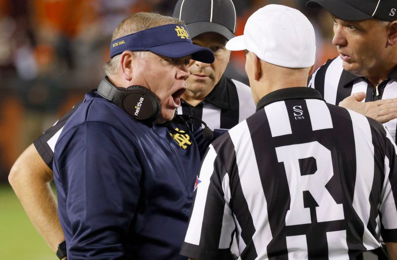 Oct 9, 2021; Blacksburg, Virginia, USA; Notre Dame Fighting Irish head coach Brian Kelly (left) has words with referee Jerry Magallanes during the second half against the Virginia Tech Hokies at Lane Stadium. Mandatory Credit: Reinhold Matay-USA TODAY Sports