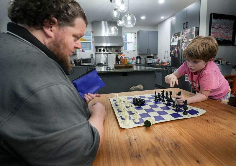 Matilda Chalmers, 9, (right) sets up a chess board with her father Alex Chalmers at their home Wednesday, March 11, 2026, in Indianapolis. Matilda Chalmers is a student at Center for Inquiry School 27 and is a member of the chess club there.