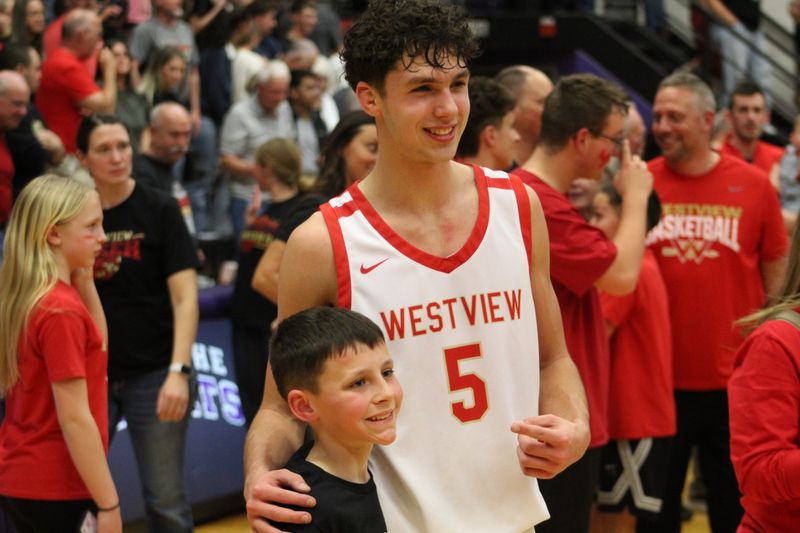 Westview junior Austin Schlabach takes a photo with a young fan after the IHSAA Class 2A North semi-state championship at the Muncie Fieldhouse on Saturday, March 21, 2026.