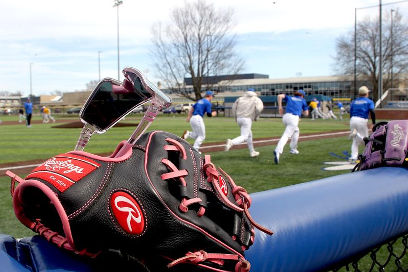 A baseball mitt and sunglasses parked on a rail mean spring time and baseball season is almost here. The Mitchell Varsity Baseball team goes through a drill before an intrasquad scrimmage on Tuesday, March 24, 2026.