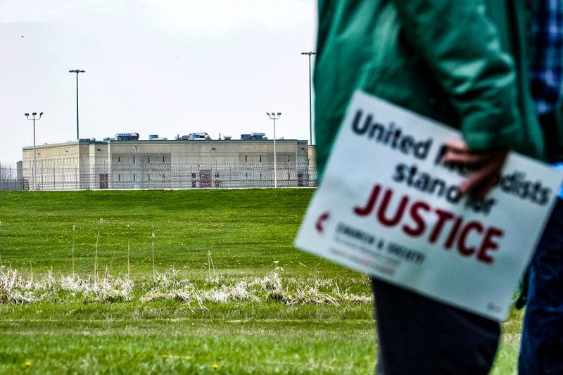 A protester holds a sign during a press conference with political and faith leaders at Miami Correctional Facility on Thursday, April 9, 2026, in Bunker Hill, Indiana.
