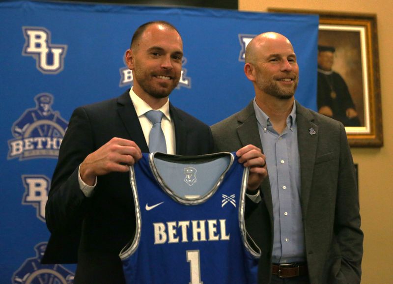 New Bethel University head men's basketball coach David Osborn (left) holds up a Pilots jersey at an introductory press conference next to Director of Athletics Jason Lewkowicz (right) Thursday, April 16, 2026, in Mishawaka.