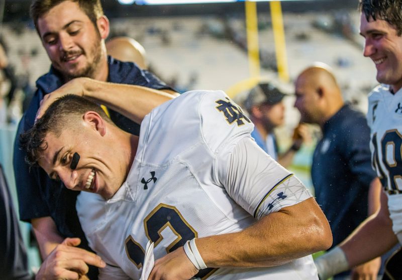 Notre Dame QB Ian Book (12) gets jokes around with QB coach Tommy Rees during the Notre Dame-North Carolina NCAA college football game Saturday, Oct. 7, 2017, at Kenan Memorial Stadium in Chapel Hill, NC. Tribune Photo/ROBERT FRANKLIN

Notre Dame Vs North Carolina