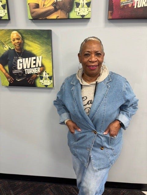 Gwen Turner poses near her staff picture at Heroes Camp.