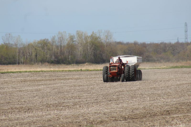 A farmer spreads dry fertilizer across a hayfield in the town of Byron, Wisconsin, during spring fieldwork.
