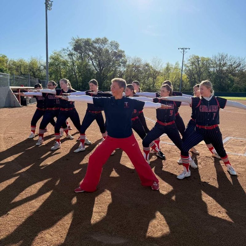 Tri-County assistant softball coach and Lafayette based yoga instructor Andrea Lantz (center) leads her team in a Warrior 2 pose at Remington Field in Remington, Indiana on Saturday, May 2, 2026.