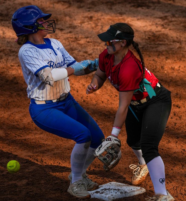 New Palestine Dragons Payton Dye (12) collides with Roncalli Royals Brooke Wolford (5) on third base Wednesday, May 6, 2026, during a softball game at Roncalli High School in Indianapolis. The Roncalli Royals defeated the New Palestine Dragons, 6-3.