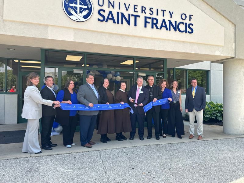 University of St. Francis President Lance Richey holds scissors to cut a ribbon in front of the newly blessed Lafayette campus. The new facility, 1415 Salem St., was donated by Franciscan Health and refurbished through an anonymous $3.5 million donation.
