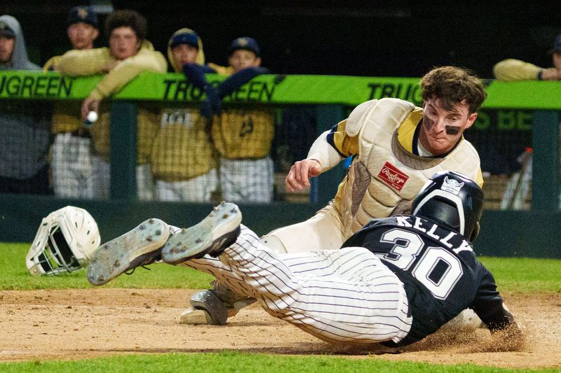 New Prairie's Reed Robinson, top, tags Penn's Caden Kelly (30) out at home plate during an IHSAA baseball game between New Prairie and Penn at Four Winds Field on Wednesday, May 13, 2026, in South Bend.