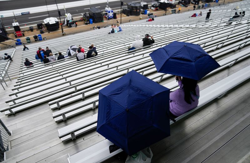 Racing fans sit through the rain Saturday, May 16, 2026, ahead of qualifying for the 110th running of the Indianapolis 500 at Indianapolis Motor Speedway.
