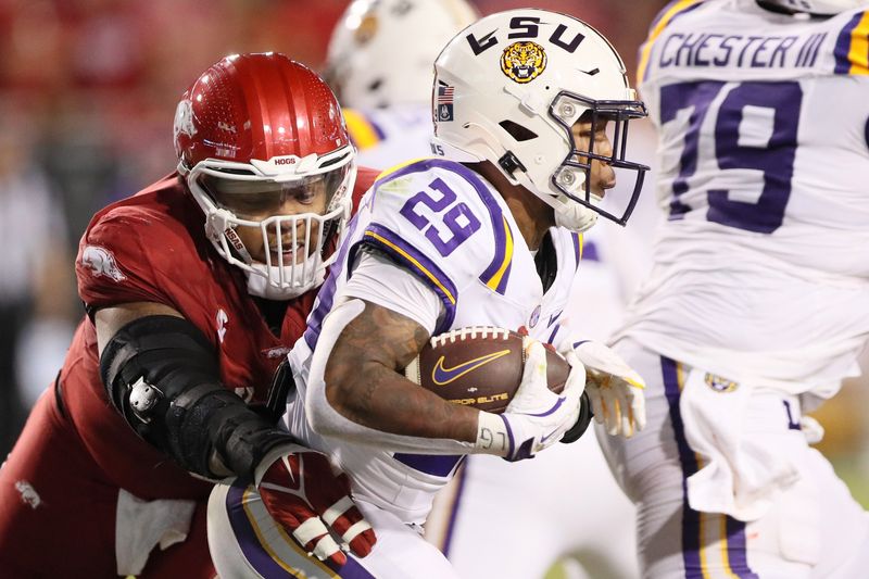 Oct 19, 2024; Fayetteville, Arkansas, USA; LSU Tigers running back Caden Durham (29) rushes in the second quarter as Arkansas Razorbacks defensive lineman Cameron Ball (5) attempts to tackle at Donald W. Reynolds Razorback Stadium. Mandatory Credit: Nelson Chenault-Imagn Images
