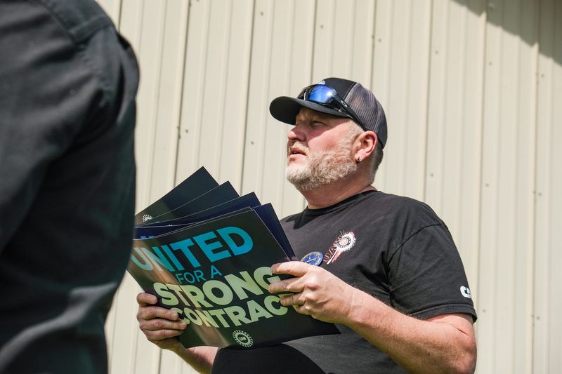 United Auto Workers 2317 Vice President Tanner Garrison hands out signs to other union members during the strike information session on May 21, 2026, before the union's strike vote.