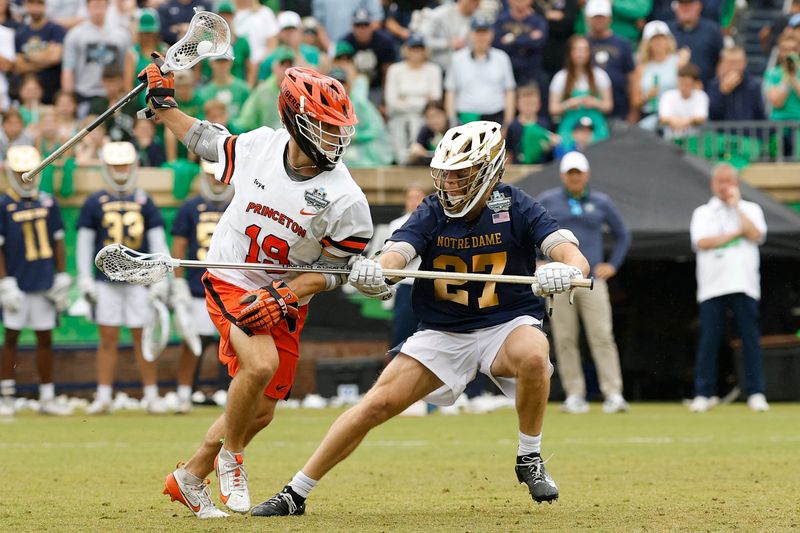 May 25, 2026; Charlottesville, VA, USA; Princeton Tigers midfielder Tucker Wade (19) runs with the ball as Notre Dame Fighting Irish defender Nate Schwitzenberg (27) defends during the first quarter in the NCAA Mens Lacrosse National Championship game at Scott Stadium. Mandatory Credit: Geoff Burke-Imagn Images