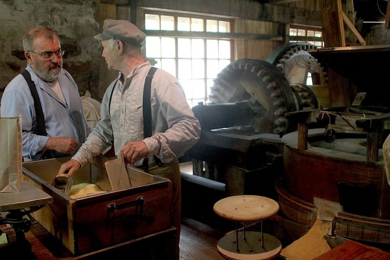 The Spring Mill Living History Weekend occurred May 23 and 24th at the Village. Pictured are Tommy Wade, left, and Bill Edwards. The two demonstrated how the mill grinds corn Saturday. The ground corn can be seen at the lower right of the picture.