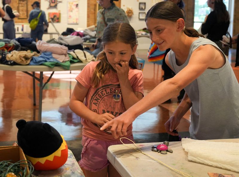 (From left) Rebecca Schott, 7, and her sister Veronica Schott, 10, look through items during the Really Really Free Market on Thursday, May 14, 2026, at the Garfield Park Arts Center in Indianapolis. Attendees looked through a variety of items, from household appliances to clothing, that were donated by other attendees.