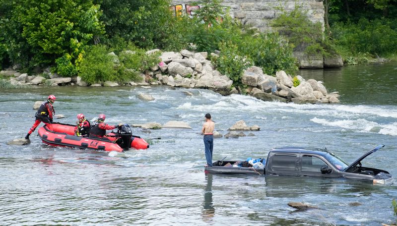 Emergency responders work to rescue a man from the bed of a truck near the Emrichsville Dam Wednesday, June 24, 2026, in the White River in Indianapolis.