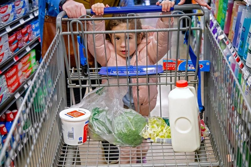 Skye Reid, 3, pushes the cart while grocery shopping with her mother Molly in Oklahoma City, Okla. on Thursday, Feb. 16, 2023.