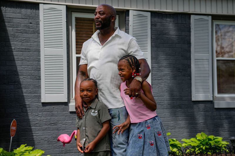 Anthony Tyrone Bailey, 61, holds his grandkids Matrell and Paislee Pope, 7, on Thursday, June 25, 2026, at his home in Indianapolis. Bailey was sentenced to 60 years in prison for a carjacking and robbery in 1997. In 2024, Bailey’s sentence was reduced and he was released. Since then, he has rebuilt his life. But now, an U.S. attorney in Indianapolis is seeking a court order to return him to prison for 25 years.