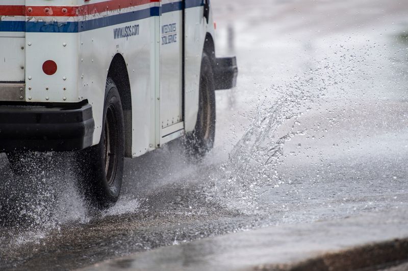 A mail truck splashes through high water in Lawndale Shopping Center Friday, June 26, 2026.