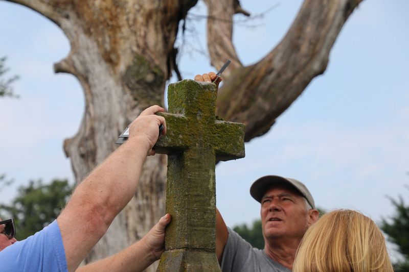 Troy Watters and volunteers work to remove decades of accumulating growth from a headstone at Beech Grove Cemetery. Watters, the cemetery's superintendent is the driving force behind a new volunteer effort to clean, repair and restore Beech Grove's headstones.