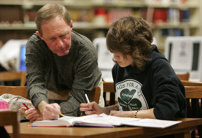 Retired basketball coach Tom DeBaets helps Joeli McLane, 14, with her algebra during a study table at Clay High School in this 2010 file photo.