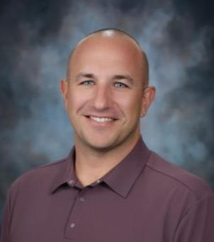 New Plymouth High School Athletic Director Ryan Welch smiles for a headshot.
