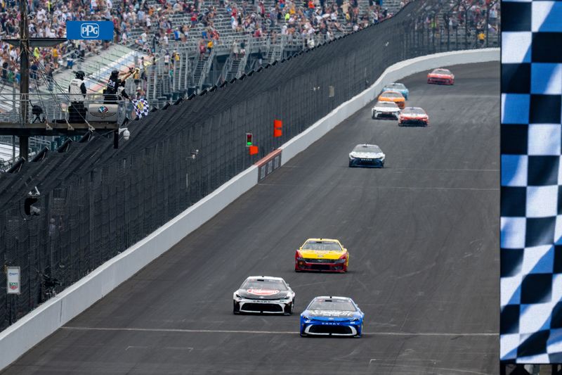 NASCAR Cup Series driver Corey Heim (67) takes the checkered flag ahead of NASCAR Cup Series driver Christopher Bell (20) to win the NASCAR Brickyard 400 Sunday, July 26, 2026 at Indianapolis Motor Speedway in Speedway, Ind.