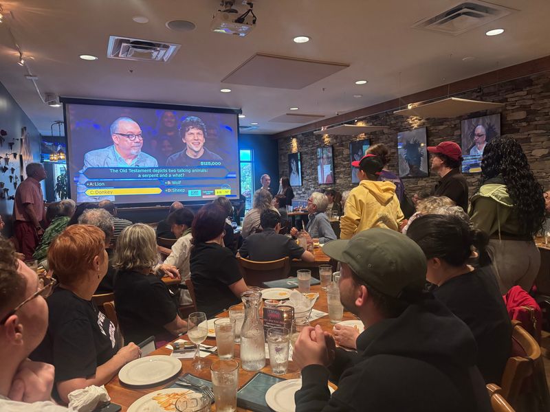 Actor Jesse Eisenberg (left, red hat) watches his episode of "Who Wants to Be a Millionaire" at Lennie's Brewpub in Bloomington Aug. 12. Eisenberg competed on the quiz show to raise money and awareness for Middle Way House, a Bloomington-based domestic violence shelter.
