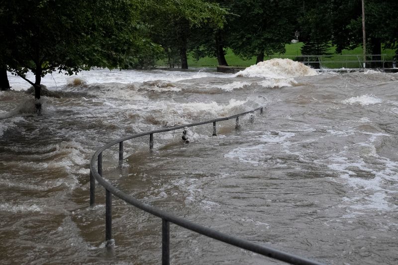 The Fall Creek rushes past its banks and over a railing Thursday, Aug. 13, 2026, at Falls Park in Pendleton.