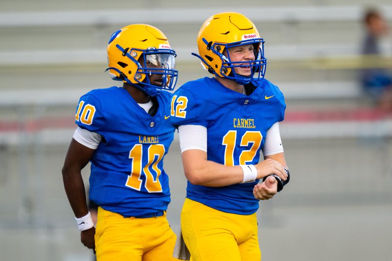 Carmel High School senior Jackson Treadway (12) and junior Mychael Lewis (10) look to the sideline for a play during an IHSAA varsity football game against Zionsville High School, Friday, Aug. 14, 2026, at Carmel High School.