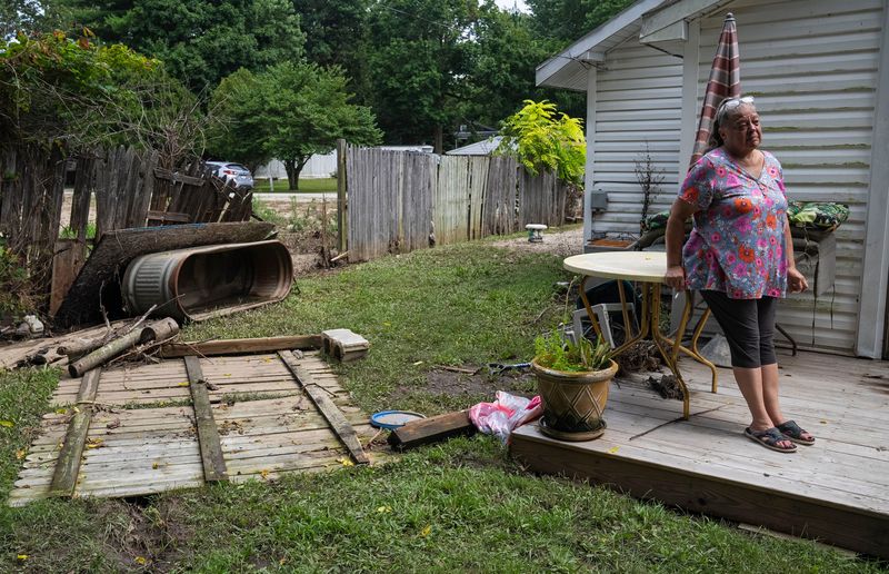 Kim Mayhew stands on her back porch Sunday, Aug. 16, 2026, at Riverwood in Noblesville. It was the first time Mayhew had seen her home since evacuating Thursday. About 3 feet of floodwater engulfed the house and lifted the well pump from the ground.