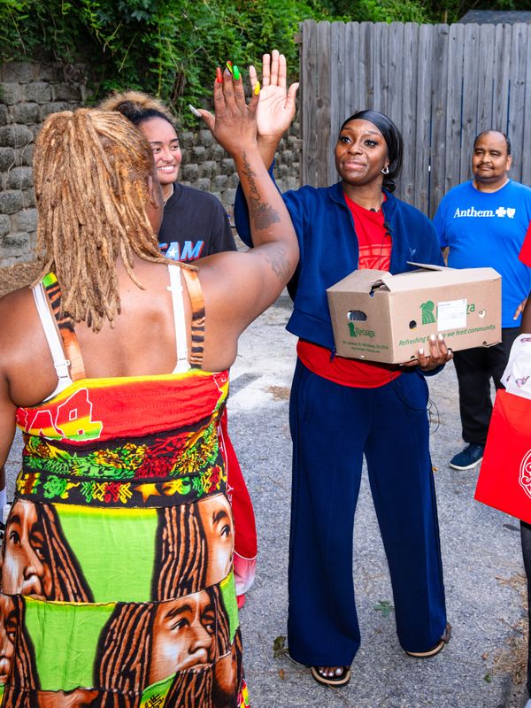 Indiana Fever rookie Raven John high-fives a resident of her hometown of Atlanta, where she delivered food while volunteering with Open Hand and Anthem.