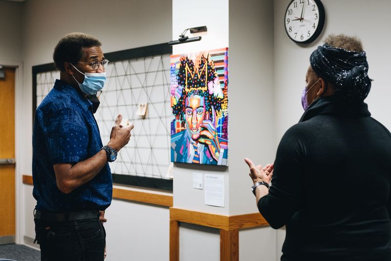Artist Joel Washington speaks with a library patron about his art in the “Our Voice” exhibit hall at the Monroe County Public Library in March 2022.