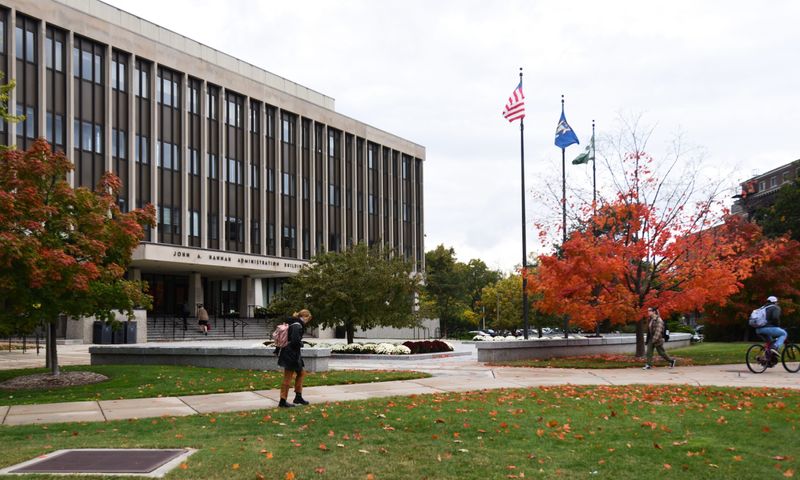 People walk past the John Hannah Administration Building on the campus of Michigan State University Thursday, Oct. 13, 2022.