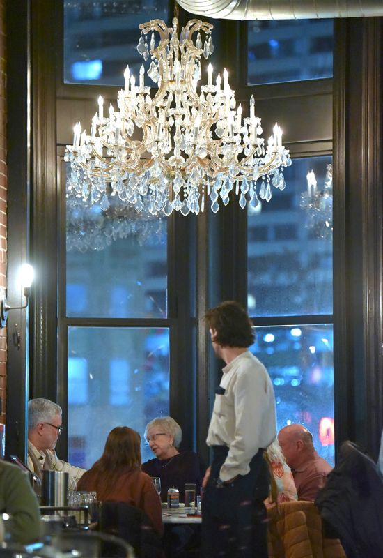 Server Tyler Lofton, right, of Detroit, makes sure everyone has what they need at table 40 as Judy Hoppin, center, of Bloomfield Hills, celebrates her 85th birthday with family, Friday night, January 20, 2023.