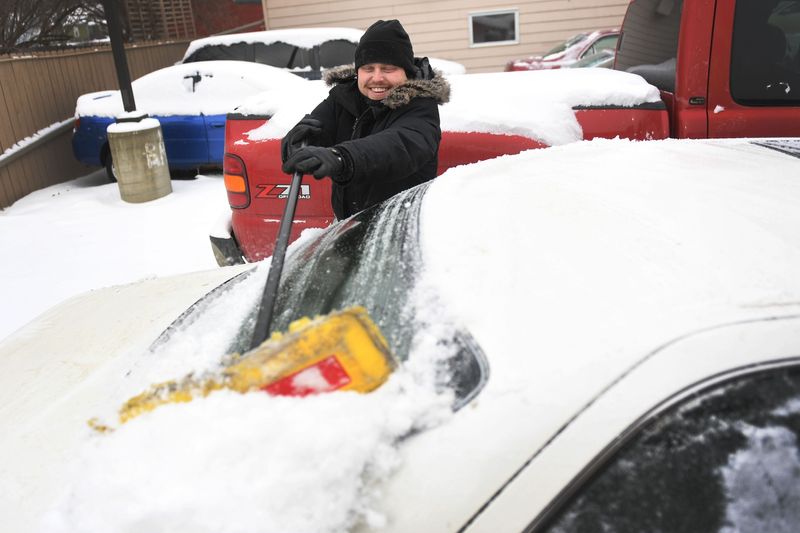 Jonathan Leise, management at Imperial Group, cleans the cars in the dealership's lot Thursday, Feb. 7, 2019, in Sioux Falls. Leise said it usually takes about two days to clean the cars, top them with gas, run them and check their batteries after it snows. Sioux Falls is under a blizzard warning until midnight.