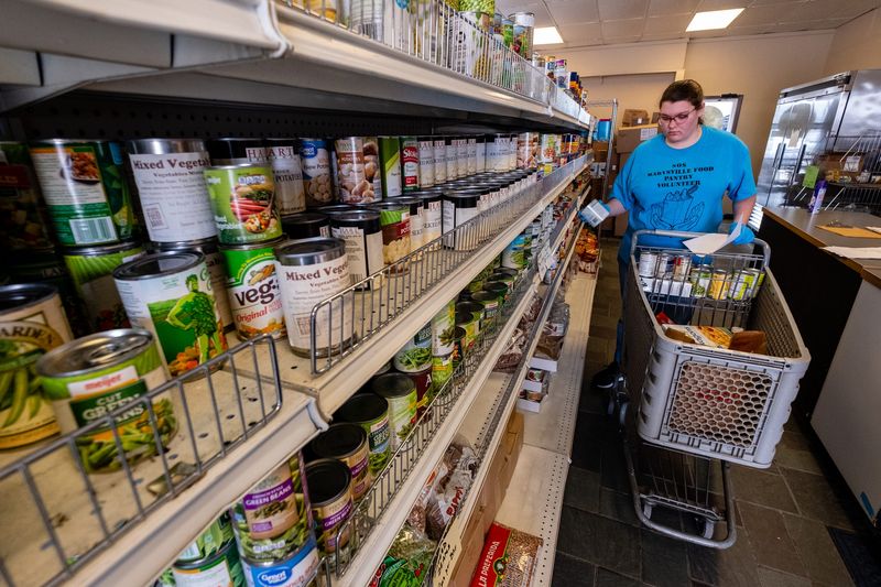 Volunteer Eyreana Warsinski, 17, fills a shopping cart Wednesday, March 18, 2020, at SOS Marysville Food Pantry. Normally visitors to the pantry are allowed in the store, but to help prevent the spread of coronavirus, they are being asked to wait in their vehicles.